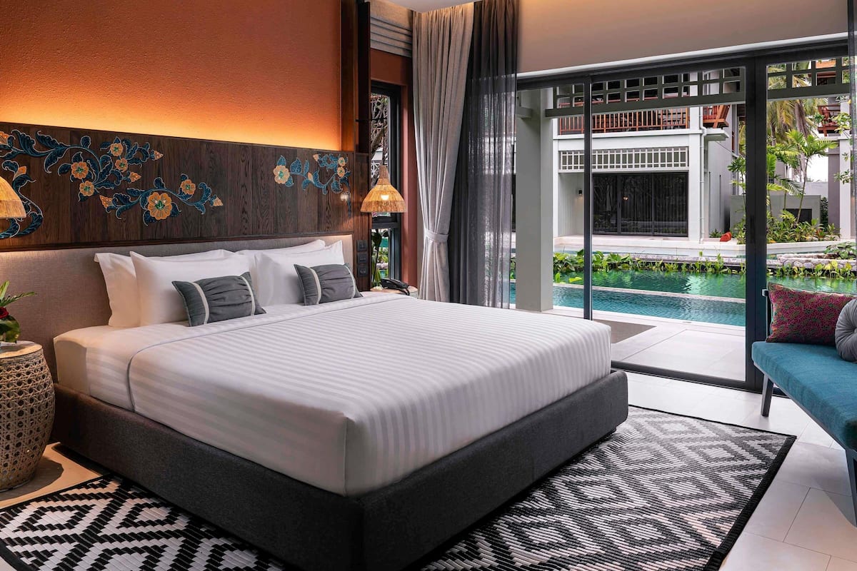 A modern bedroom with a large bed, a view of a swimming pool, and a balcony.