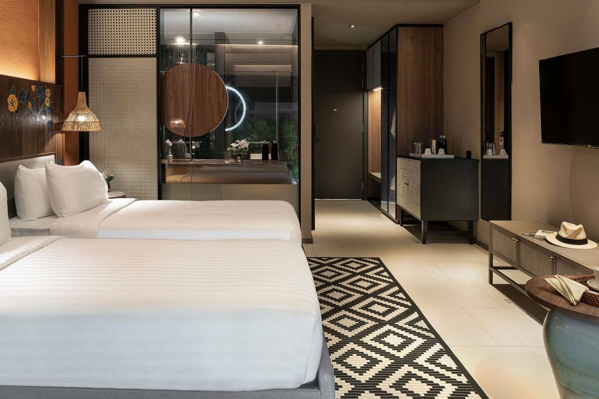 Ein modernes Hotelzimmer mit einem großen Bett, einem Schreibtisch, einem Spiegel und einem Fernseher.