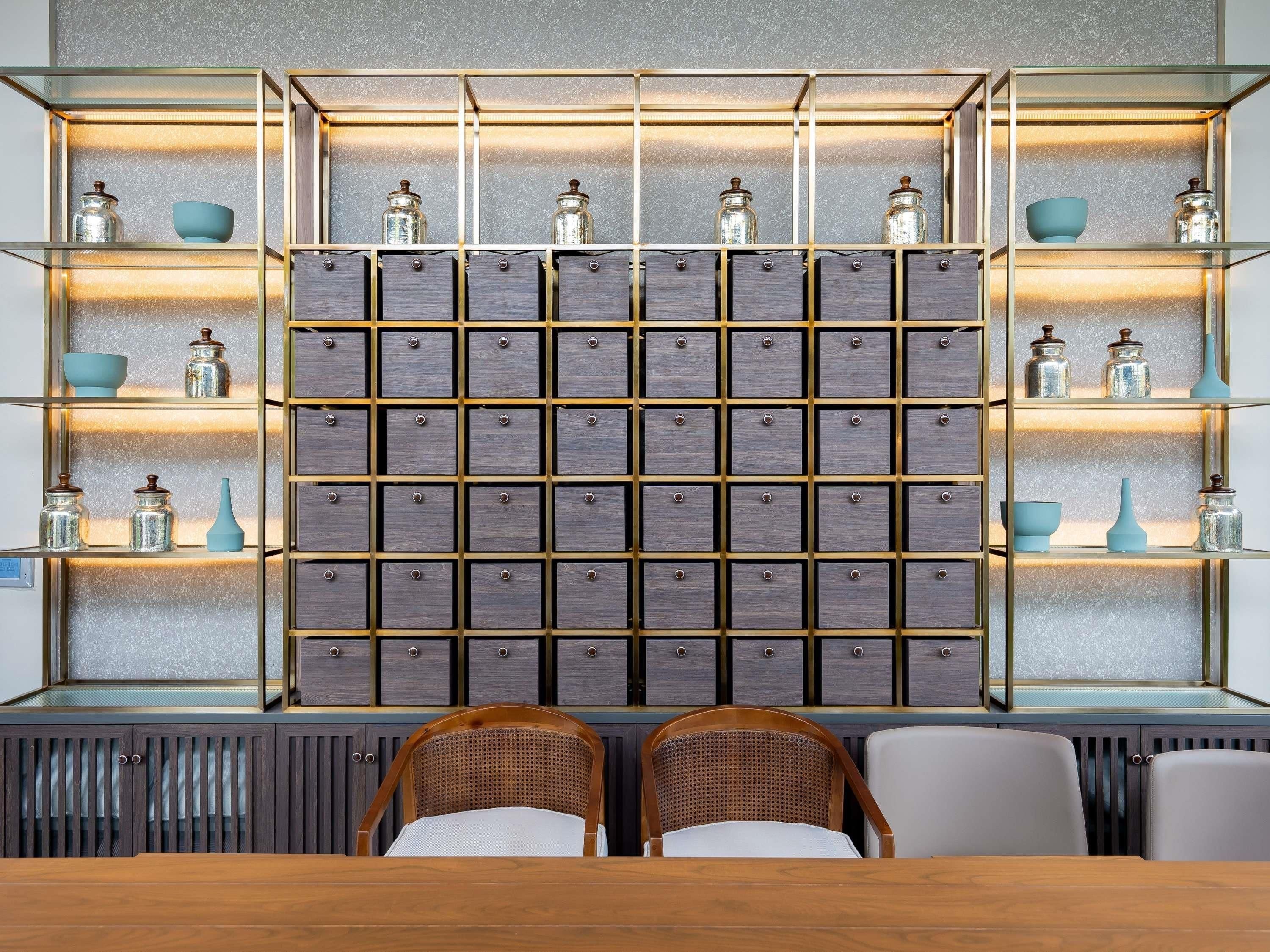 A room with a wall-mounted storage unit, two wicker chairs, and a wooden table.