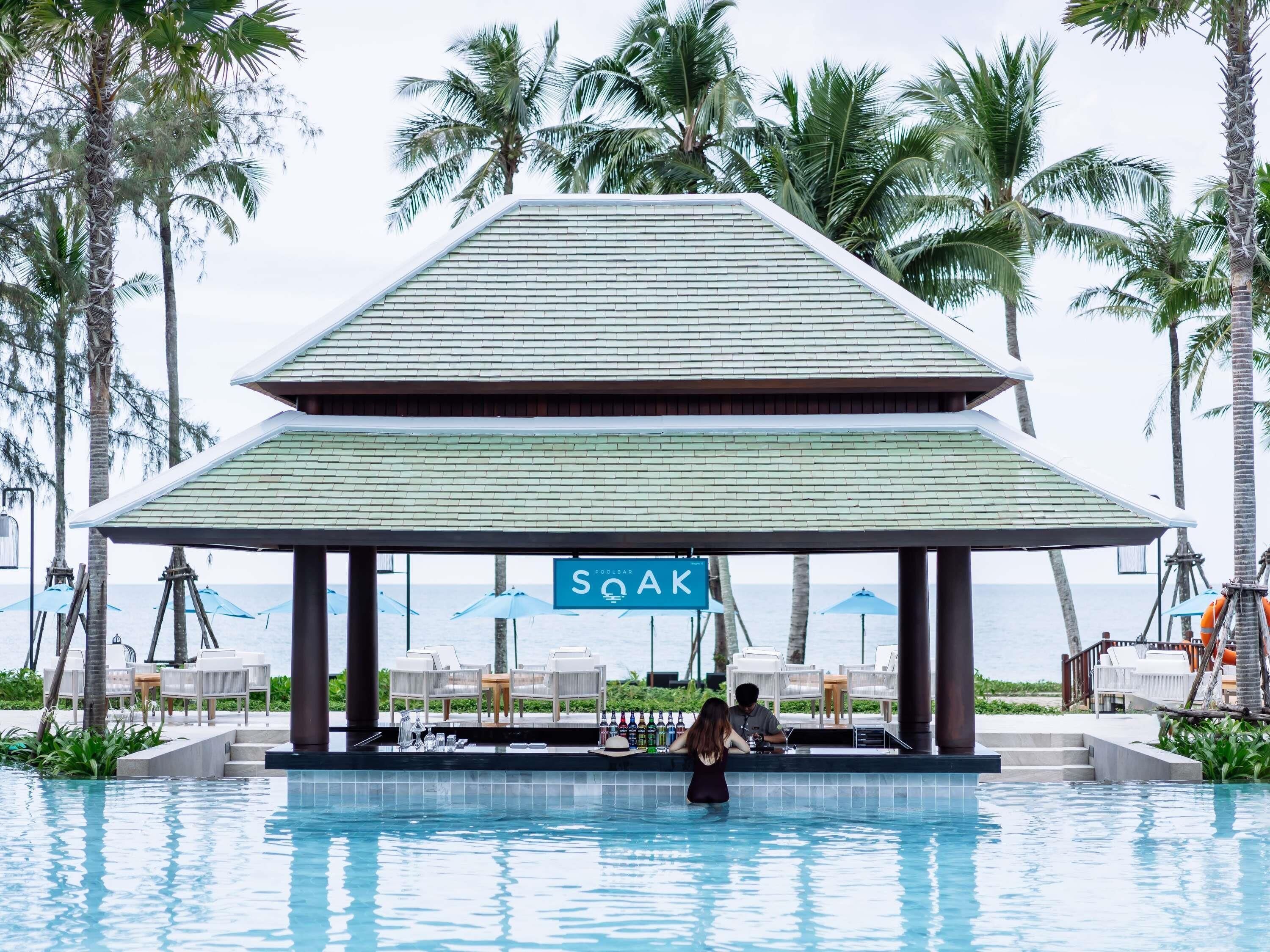 A pool area with a covered seating area, a bar, and a sign that reads 'SOAK'.