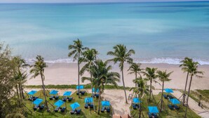 A beach view with palm trees and blue umbrellas. - Grand Mercure Khao Lak Bangsak (Takua Pa)