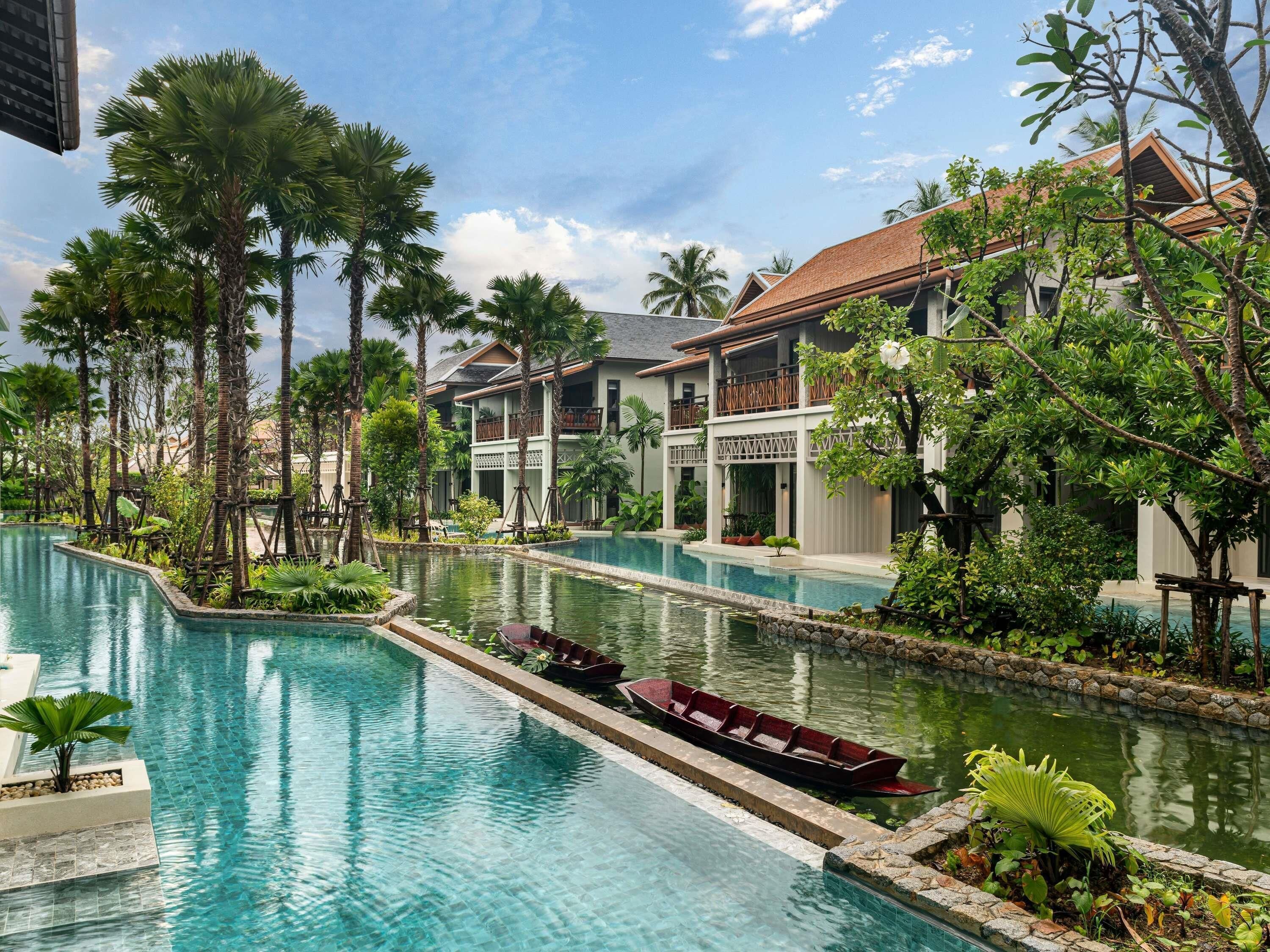 Un resort con piscina, palmeras y un barco.
