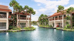 A resort with a swimming pool, palm trees, and buildings with balconies. - Grand Mercure Khao Lak Bangsak (Takua Pa)