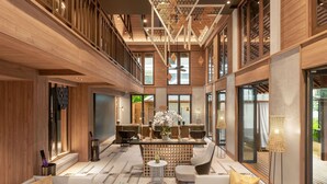 A spacious, modern interior with a high ceiling, wooden paneling, and a central seating area with sofas and a coffee table. - Grand Mercure Khao Lak Bangsak (Takua Pa)