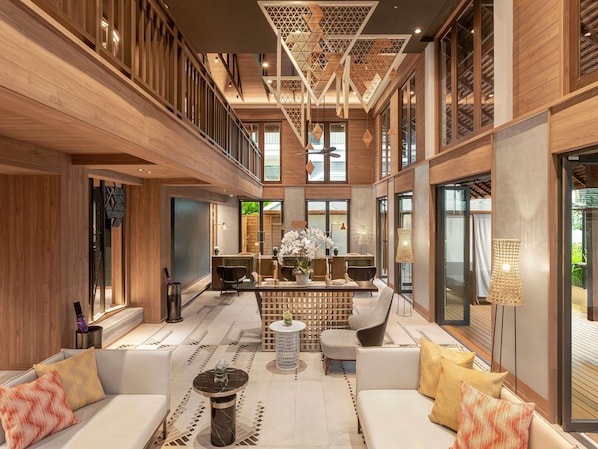 A spacious, modern interior with a high ceiling, wooden paneling, and a central seating area with sofas and a coffee table. - Grand Mercure Khao Lak Bangsak (Takua Pa)