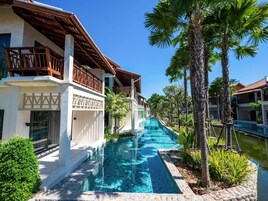 Resort com piscina, palmeiras e arquitetura moderna.