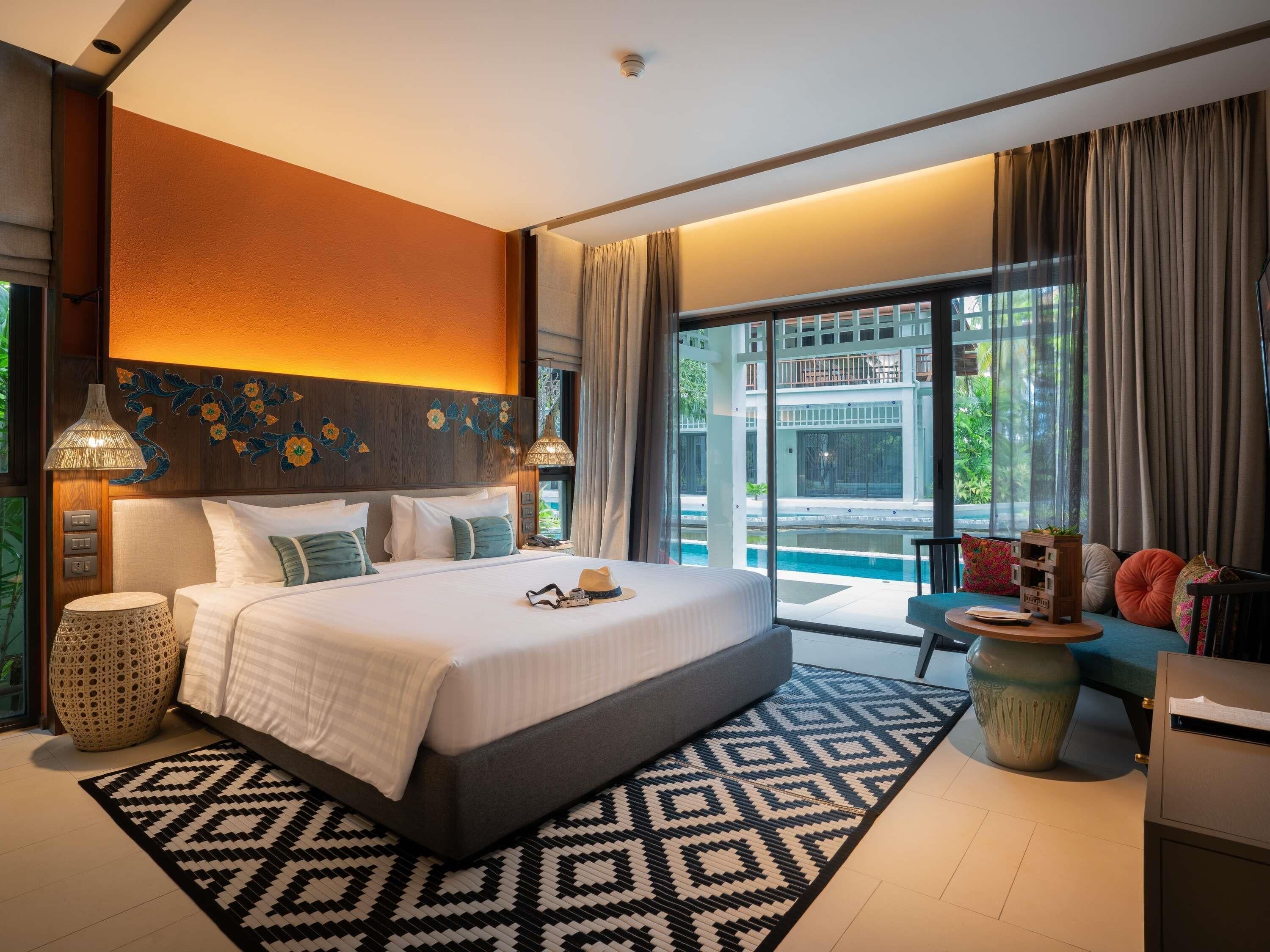 Un grand lit avec un tapis à motifs, une lampe de chevet et une vue sur une piscine.