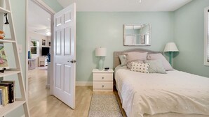 A bedroom with a bed, bedside tables, a mirror, and a door leading to another room. - River Hideaway Retreat (Southport)