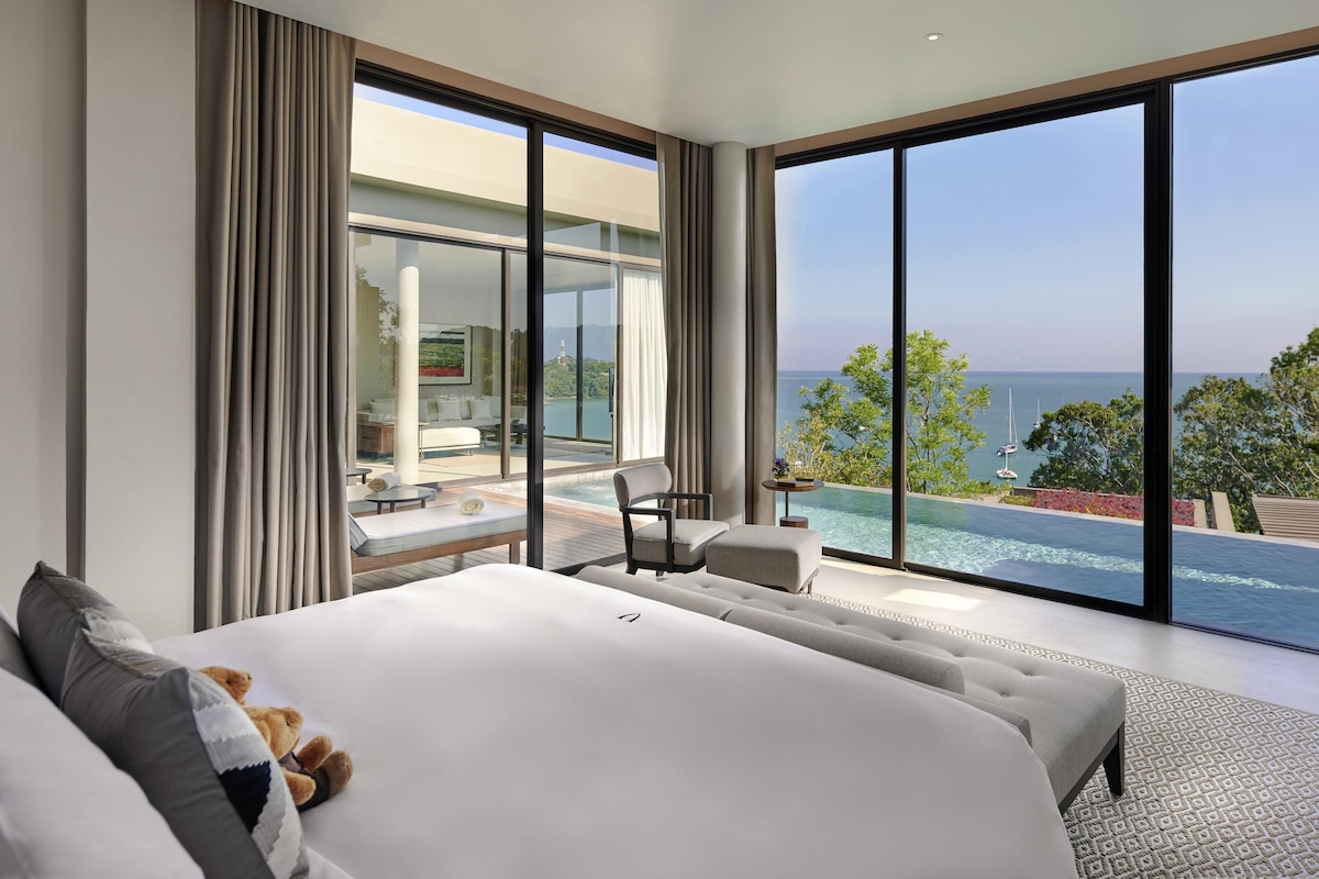 Een moderne slaapkamer met een groot bed, uitzicht op zee en een overloopzwembad.