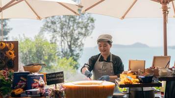 Un chef preparando comida al aire libre con vista al mar.