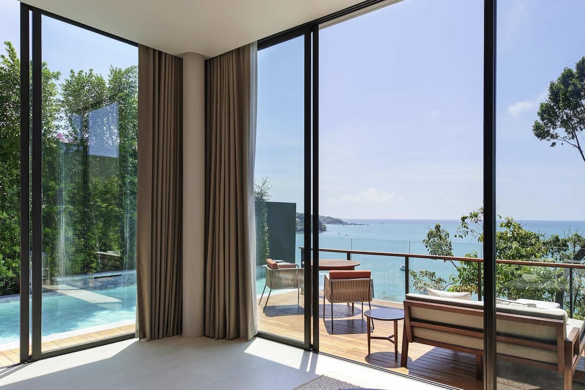 A modern room with large windows, a pool, and a view of the sea.