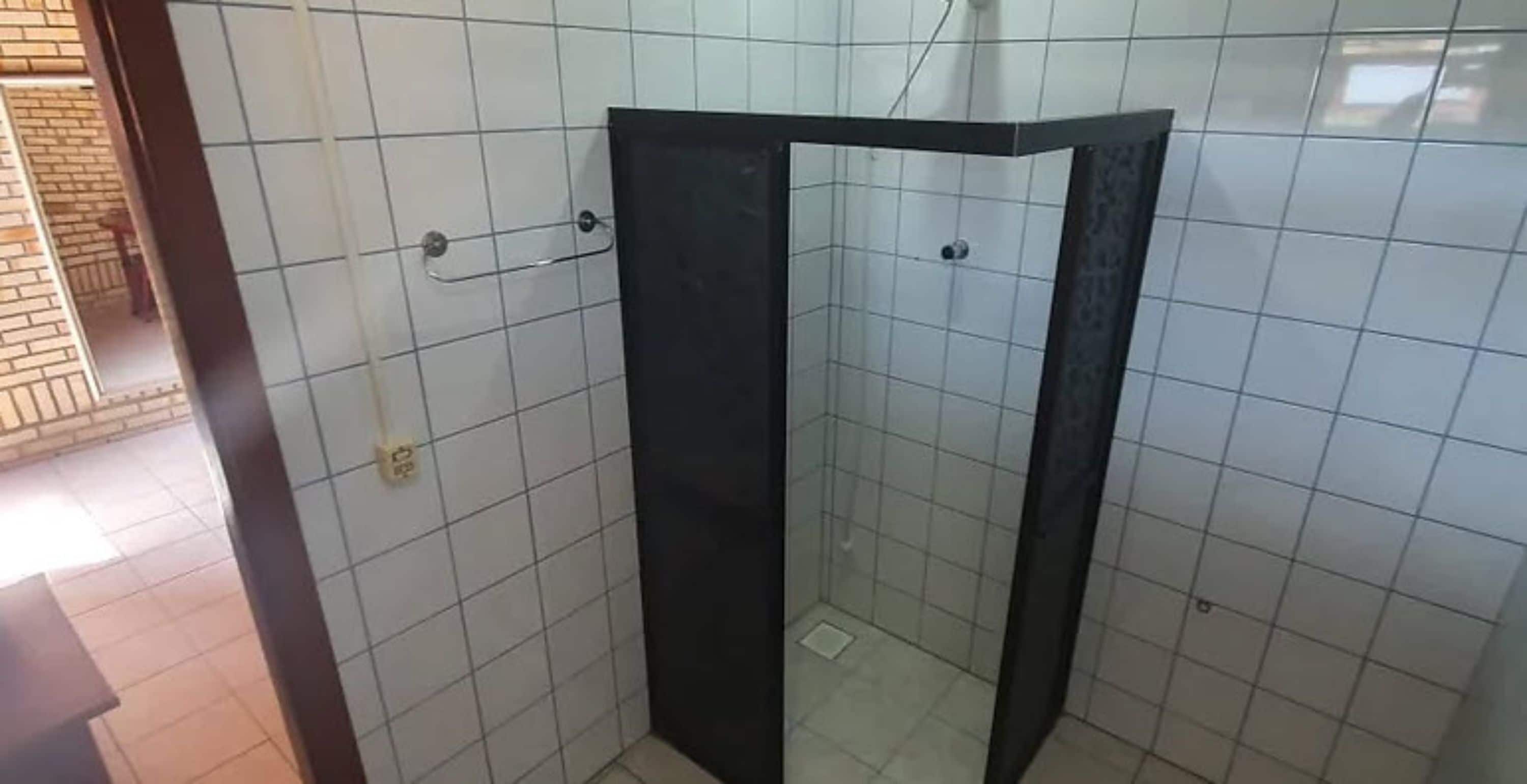 Et badeværelse med hvide flisevægge og et brusekabine i sort.