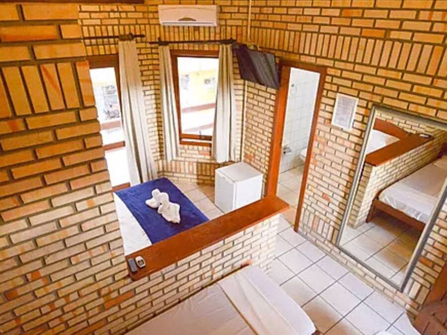 Une pièce avec un mur en briques, une fenêtre, un lit et une petite table de chevet.