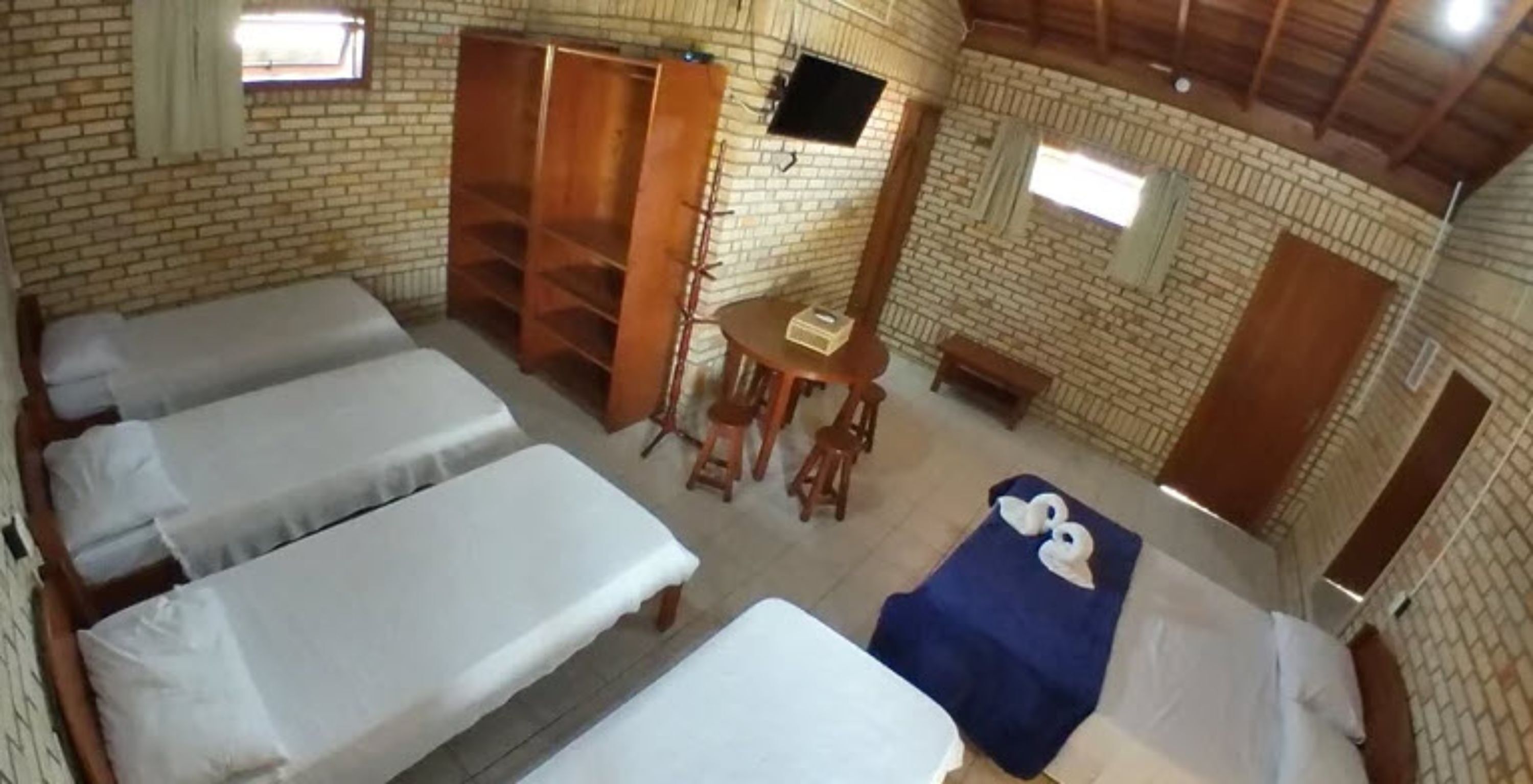 A room with four beds, a TV, and a small table with chairs.