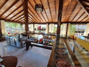 A breakfast buffet area with a wooden ceiling and large windows. - Pousada MaunaLoa (Garopaba)