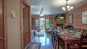 Una sala da pranzo in legno con camino, tavolo imbandito per sei persone e vista sull'esterno.