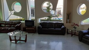 Un salon moderne avec deux canapés en cuir, une table basse en verre et un téléviseur à écran plat.
