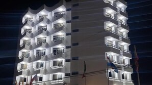 Un hôtel à plusieurs étages, doté de balcons et surmonté d’une grande enseigne « HLEO ».