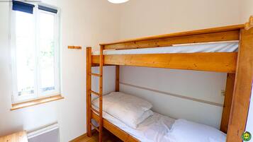 A bunk bed room with a window, a wooden ladder, and a small table.
