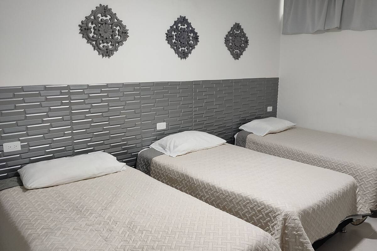 A hotel room with two single beds, a brick-patterned headboard, and decorative wall sconces.