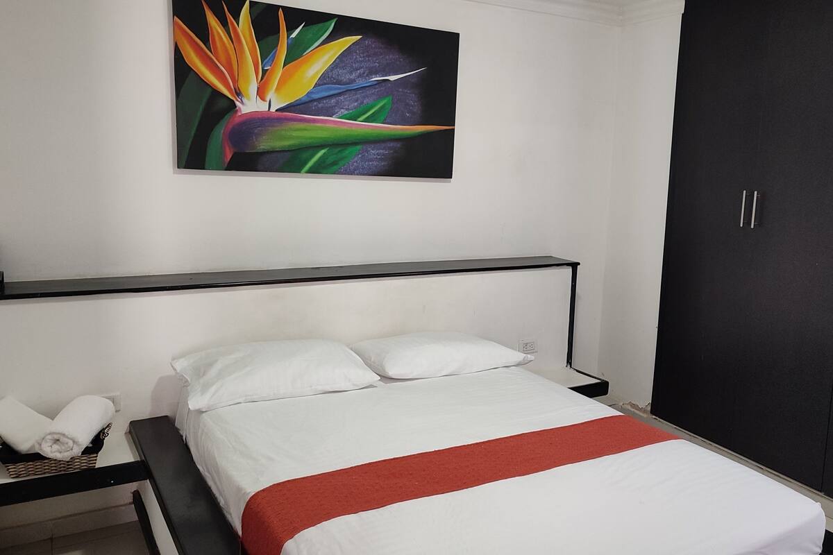A hotel room with a bed, a nightstand, a wardrobe, and a painting on the wall.