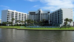 Een modern hotel met meerdere verdiepingen, een zwembad en palmbomen.