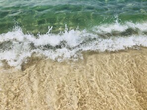 Uma praia de areia com águas claras e ondas.
