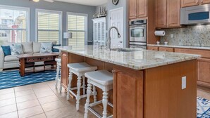 A kitchen with wooden cabinets, a marble countertop, and a built-in microwave. - Amazing 4 Bedroom Sunset Island Townhome with Bonus Den! (Ocean City)