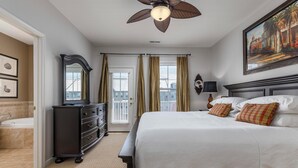 A hotel room with a large bed, a dresser, a mirror, a ceiling fan, and a painting on the wall. - Amazing 4 Bedroom Sunset Island Townhome with Bonus Den! (Ocean City)