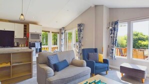 Ein geräumiger Wohnbereich mit Sofa, Sesseln, Couchtisch und Fernseher.