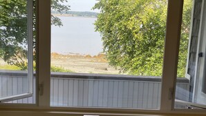 A room with a view of a lake, a wooden deck, and a white railing. - Fox Run Ocean Cottage (Trenton)
