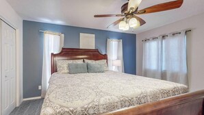 Un dormitorio con una cama de madera, un ventilador de techo y una mesita de noche.