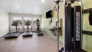 A gym with treadmills, a stationary bike, and a weightlifting station. - WoodSpring Suites Fort Mill (Fort Mill)
