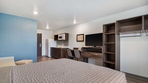 A compact room with a bed, a desk, a television, and a kitchenette. - WoodSpring Suites Fort Mill (Fort Mill)