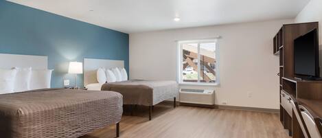 A hotel room with two beds, a TV, and a window with blinds.
