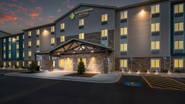 A multi-story hotel with a prominent entrance, a covered waiting area, and a parking lot with handicapped accessibility. - WoodSpring Suites Fort Mill (Fort Mill)