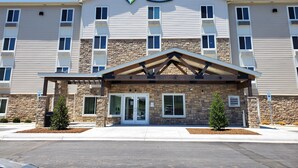 Un hôtel Woodspring Suites doté d’une façade en pierre, de nombreuses fenêtres et d’une entrée abritée.