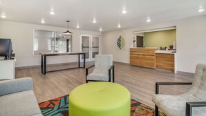 A modern interior with a reception desk, seating area, and a kitchenette. - WoodSpring Suites Fort Mill (Fort Mill)