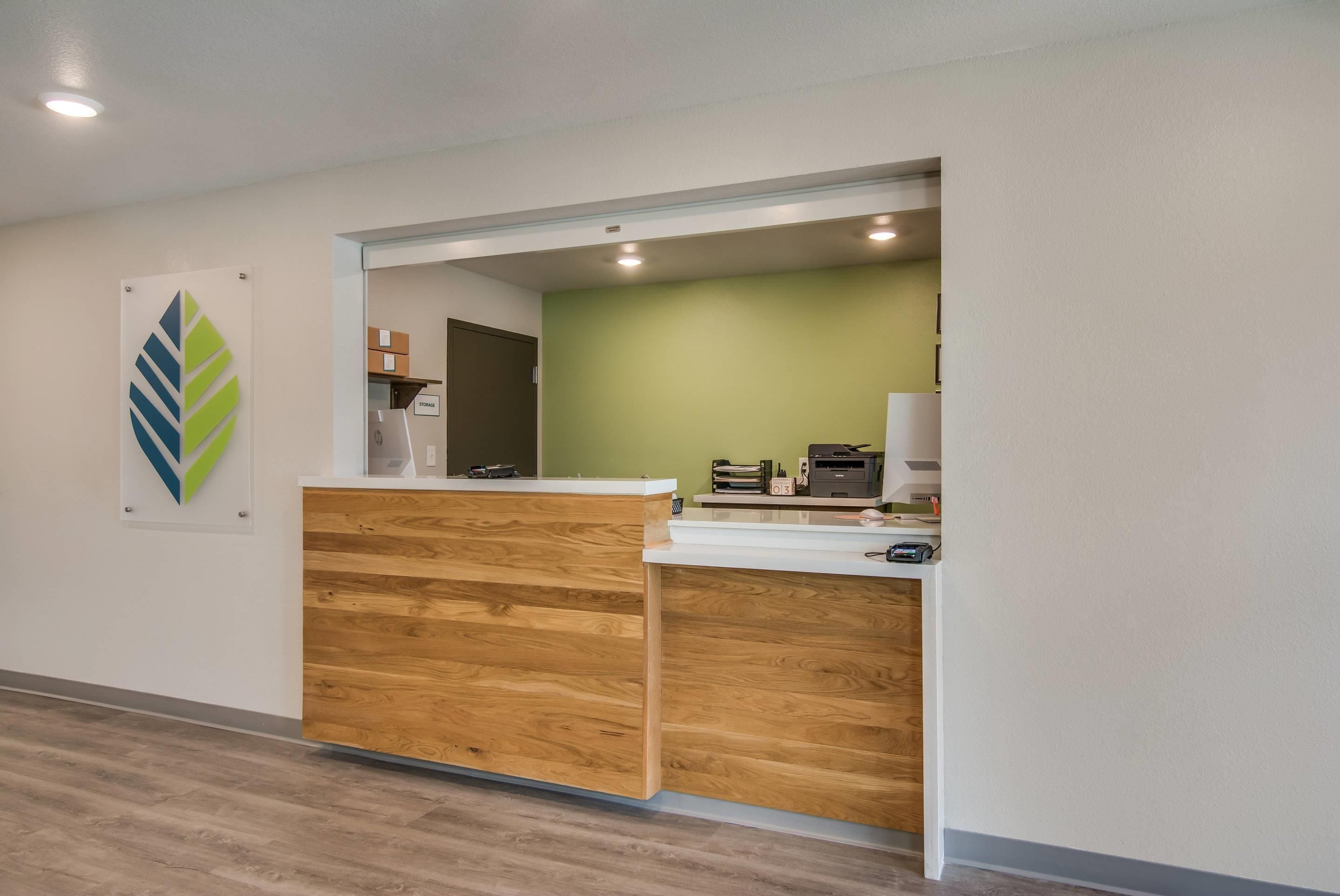 A reception desk with a wooden panel design, a storage area, and a green wall in the background.