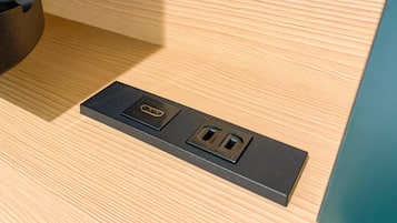 Un enchufe empotrado en la pared con dos tomas de corriente y un puerto USB sobre una superficie de madera.