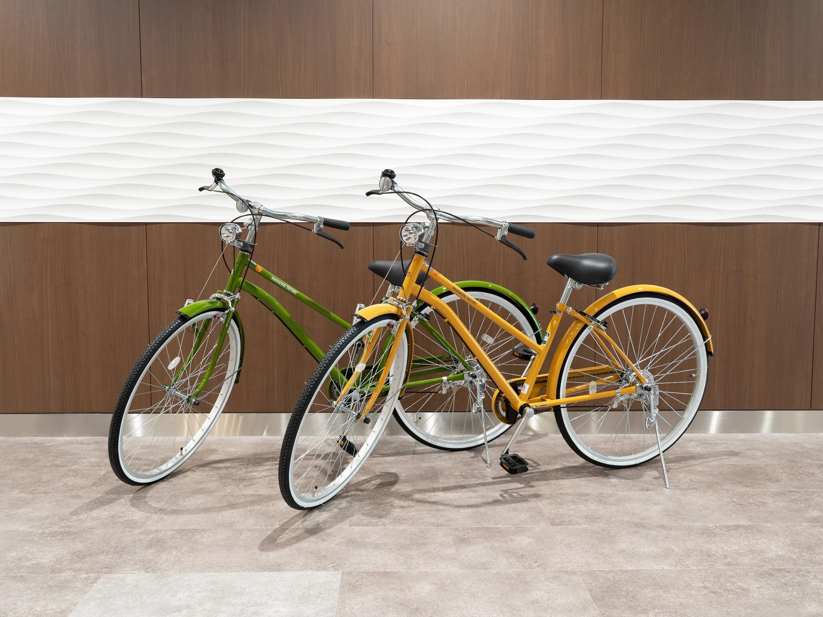Two bicycles parked against a wooden wall with a tiled floor.
