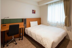 Ein Hotelzimmer mit einem Bett, einem Schreibtisch mit Stuhl und einem Vorhangfenster.