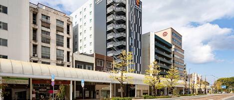 A modern hotel with multiple floors, a covered walkway, and a tram line.