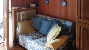 A cozy living room with a floral sofa, a decorative ceiling light, and wall-mounted plates.
