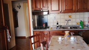 A kitchen with wooden cabinets, a tiled backsplash, and a dining table set with cups and a pitcher.