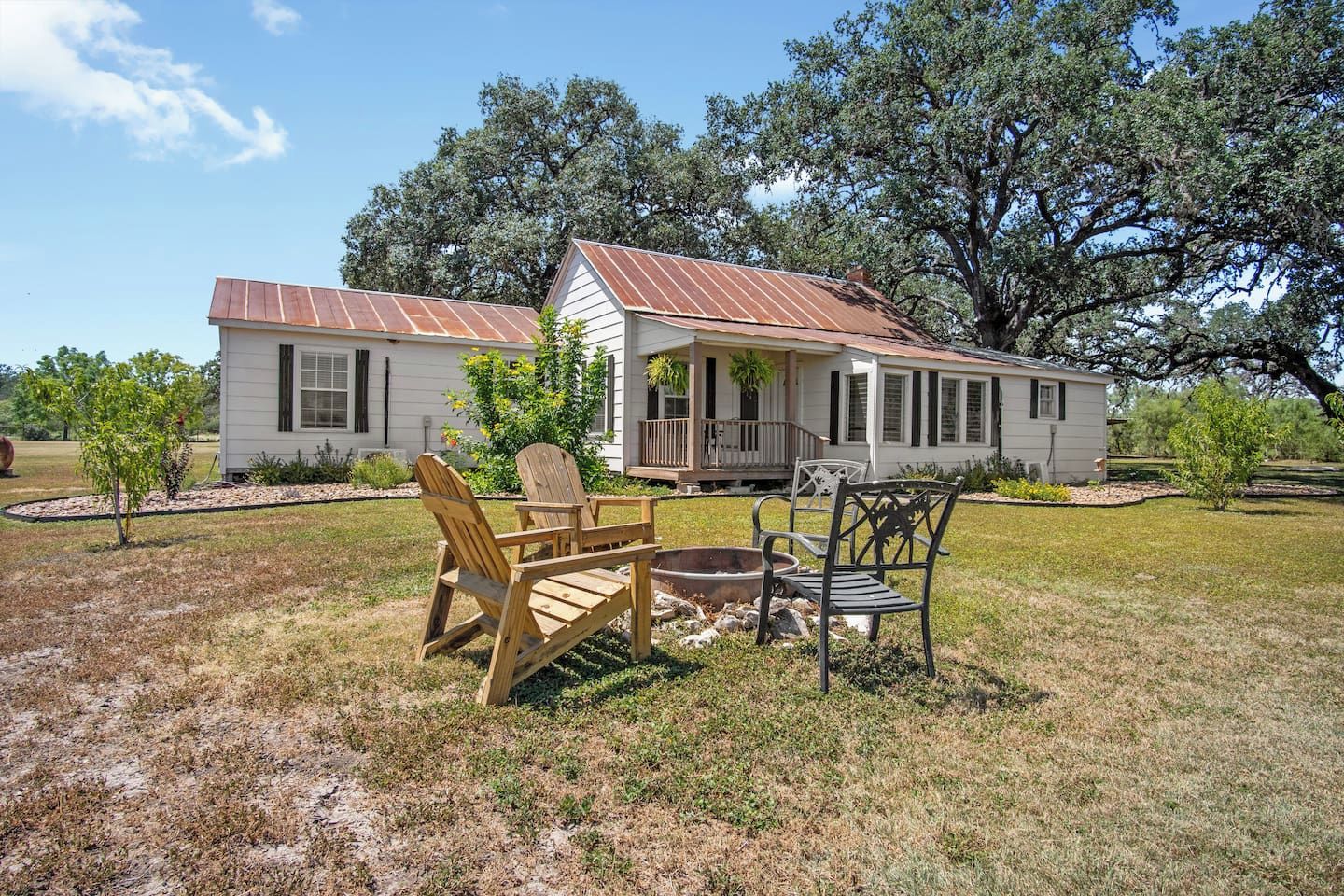A two-story house with a porch, a fire pit, and outdoor seating.