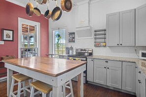 A kitchen with a wooden island, grey cabinets, and a stainless steel stove. - Mighty Oaks Retreat | 2BR Farmhouse w/ Fire Pit (D'Hanis)