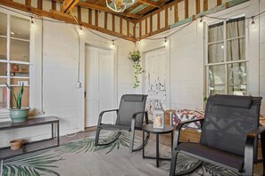 A room with a wooden ceiling, a table with chairs, a potted plant, and a window with curtains. - Mighty Oaks Retreat | 2BR Farmhouse w/ Fire Pit (D'Hanis)