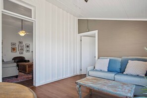 Ein Wohnzimmer mit einer Couch, einem Holztisch und einem Deckenventilator.