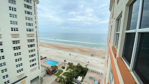 Un immeuble de grande hauteur offrant une vue sur une plage et une piscine.